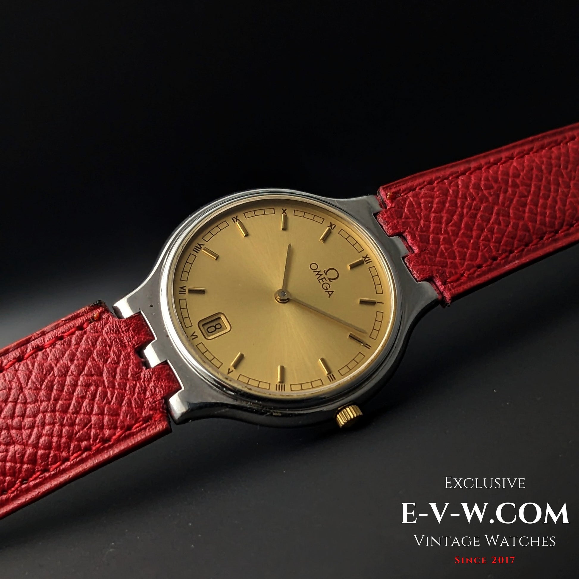Close-up of 1957 Omega vintage watch with gold dial and red leather strap, showcasing elegant Roman numeral markers and date window.