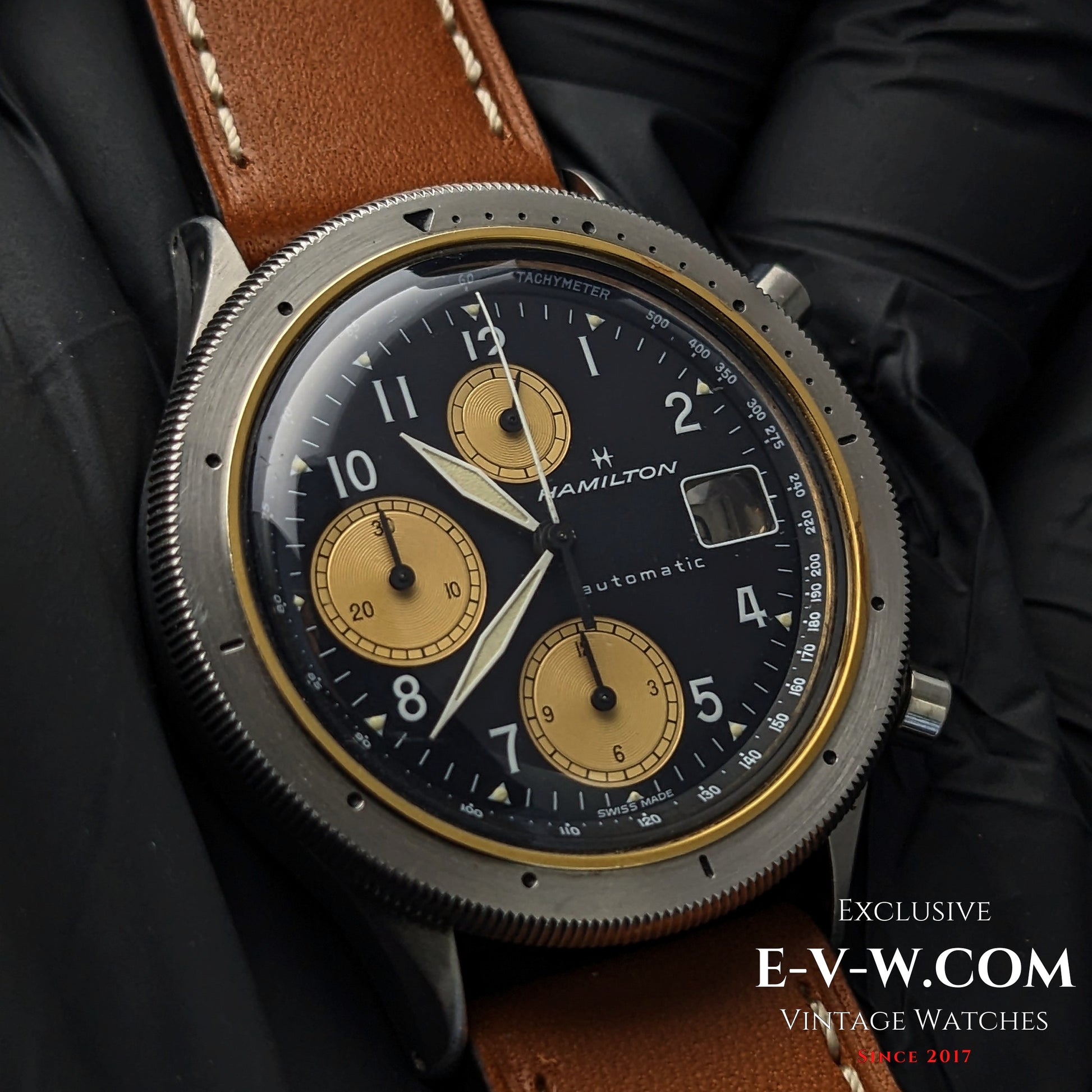 Vintage Hamilton Lancaster Chronograph with black and gold dial, automatic movement, and brown leather strap, ideal for collectors.