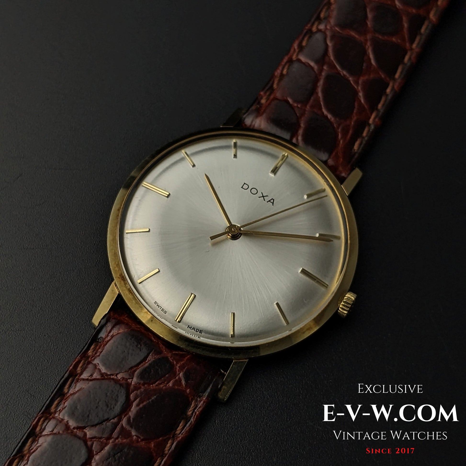 Close-up of DOXA Vintage 14k Gold Watch 1950 featuring a polished gold case, silver dial, and brown crocodile leather strap for a sophisticated look.