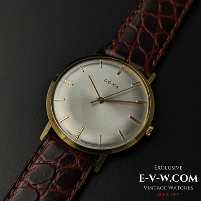 Close-up of DOXA Vintage 14k Gold Watch 1950 featuring a polished gold case, silver dial, and brown crocodile leather strap for a sophisticated look.