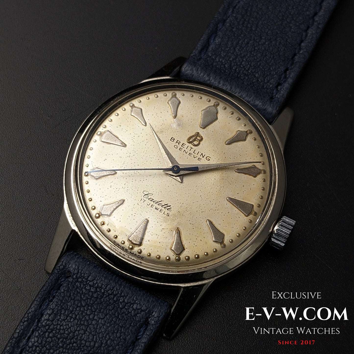 Close-up of Vintage Breitling Geneve Cadette Watch 1960s highlighting patina on dial and 17-jewel movement with blue leather strap.