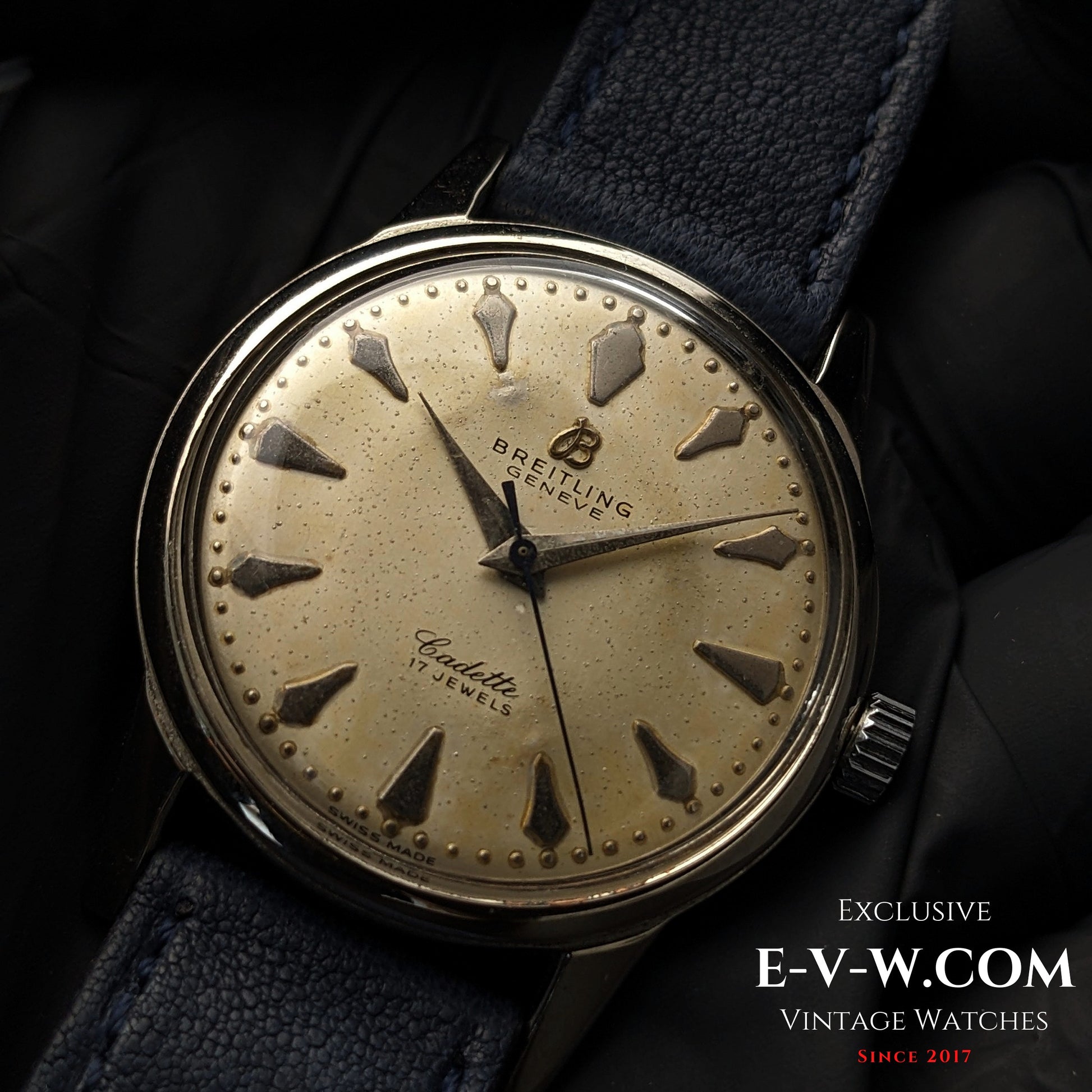 Detailed shot of Vintage Breitling Geneve Cadette Watch 1960s dial with bold hour markers and vintage patina on cream background.